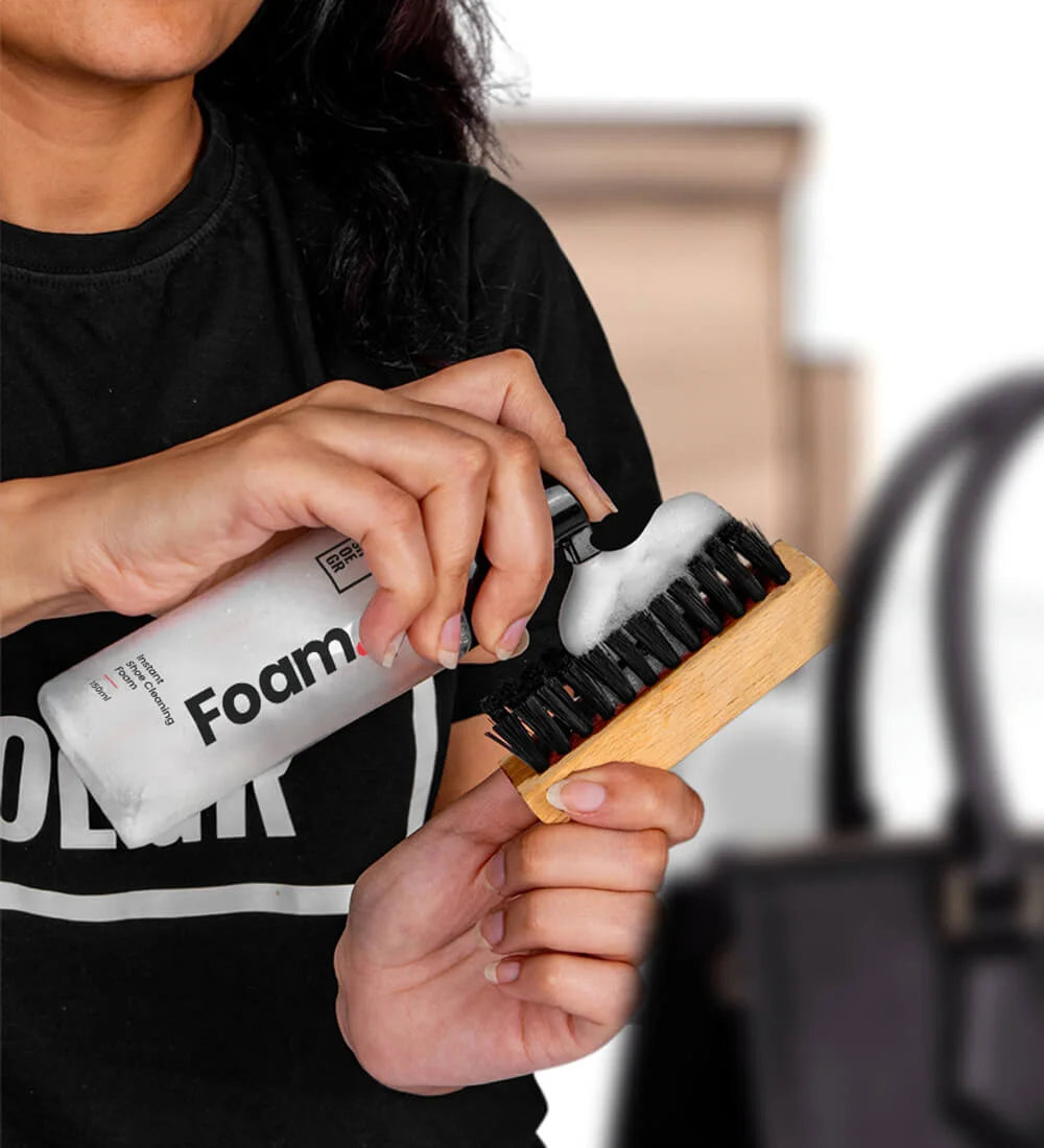 Applying shoe cleaner foam onto a brush for cleaning