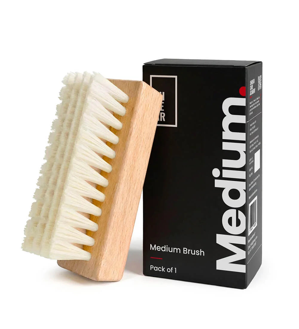 SHOEGR Medium brush with wooden handle and white PP bristles next to its packaging on a white background