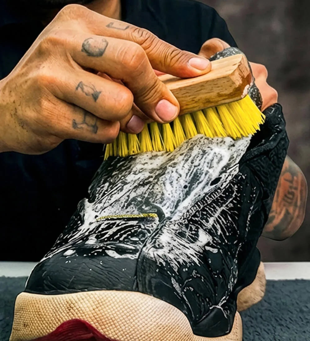 Person cleaning a black sneaker uppers with the SHOEGR Soft Brush and Solution