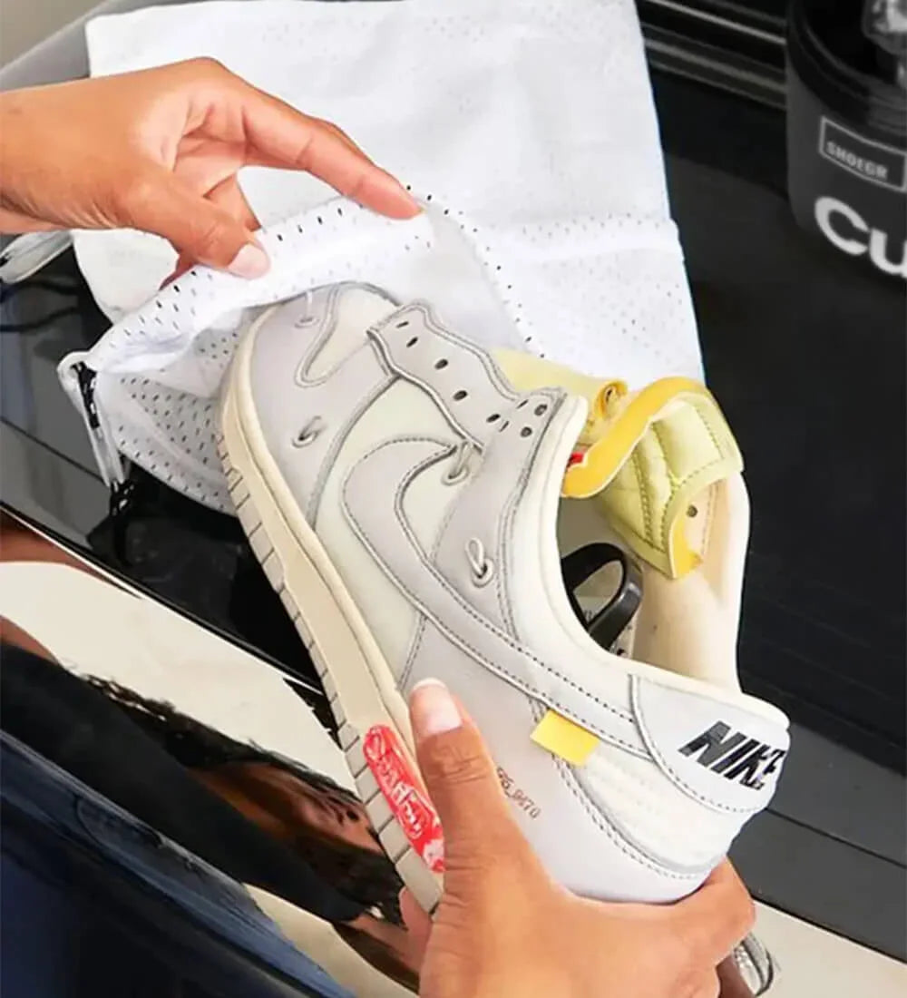 Inserting shoes into mesh laundry bag before washing