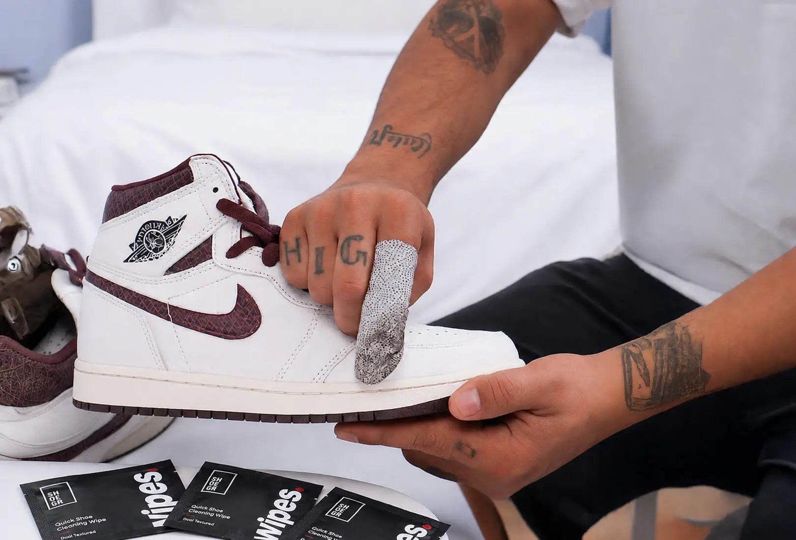 Person cleaning a white nike sneaker with maroon accents with a SHOEGR sneaker wipe