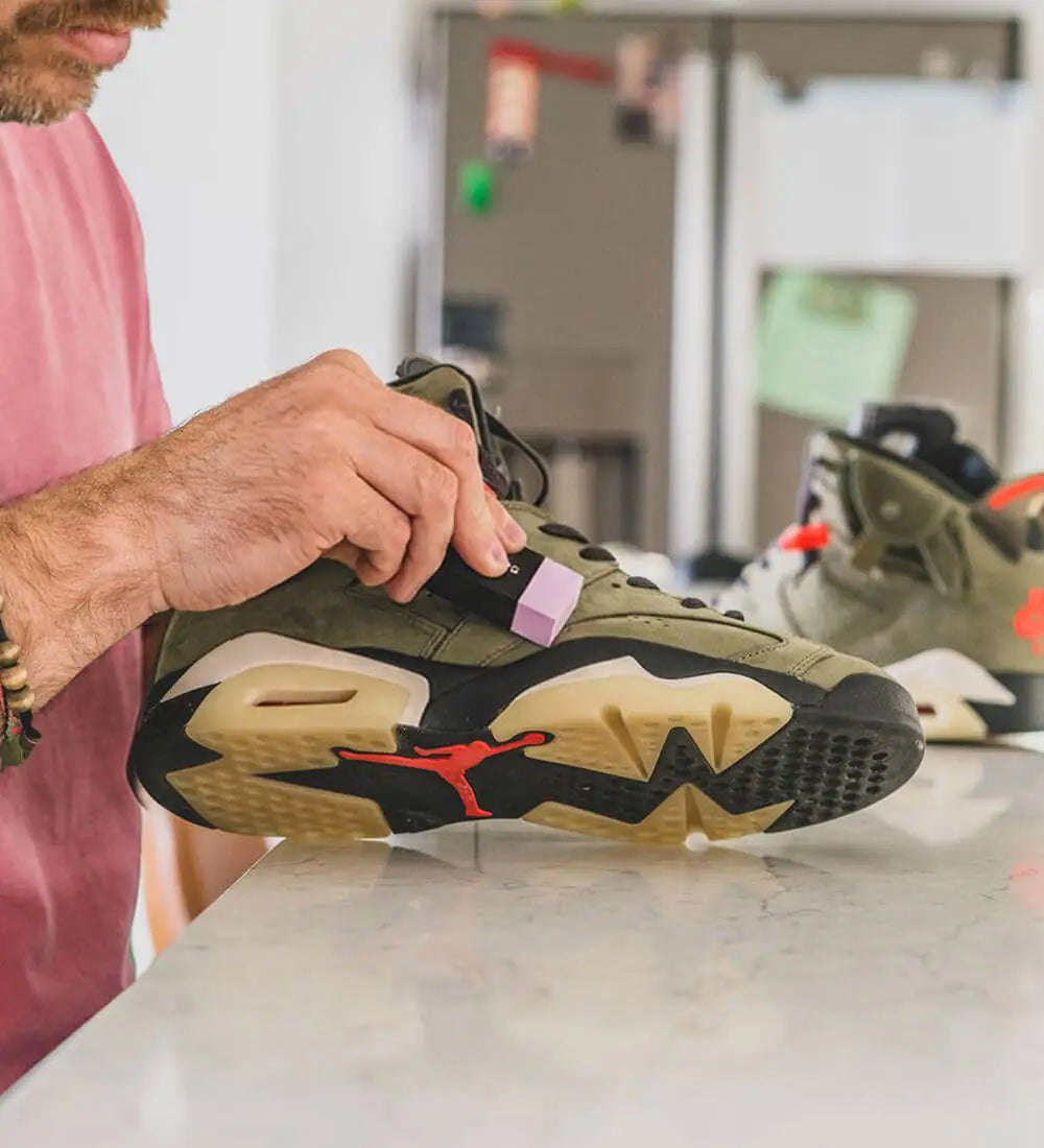 a man cleaning a nike air jordan sneaker with shoegr suede eraser